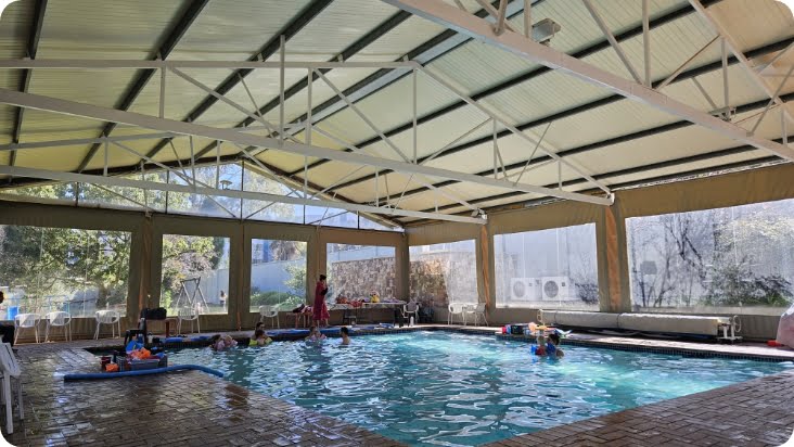 Covered indoor swimming pool at Zogs Swim School with natural light, safe surroundings, and children enjoying a lesson.