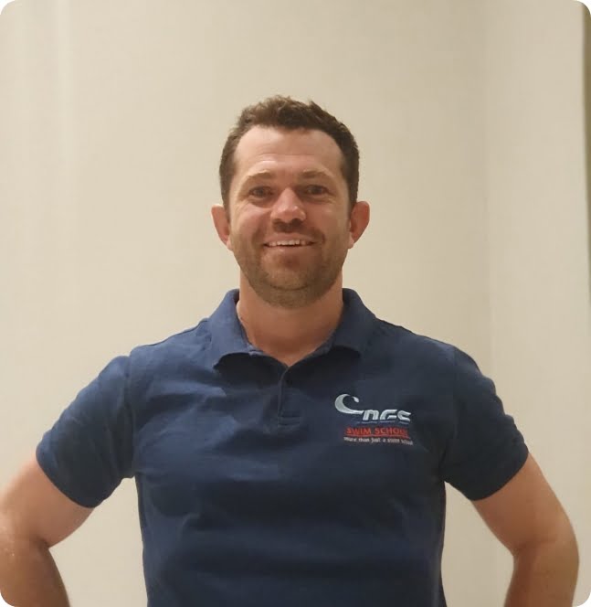 Grant Zogbhy, founder of Zogs Swim School, smiling and wearing a branded navy polo shirt.